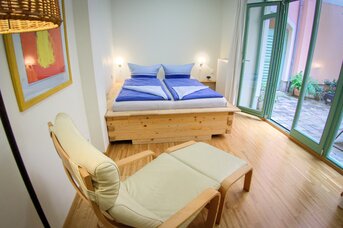 Großes Bett und Relax-Stuhl in dem Ferien-Apartment CANALETTO